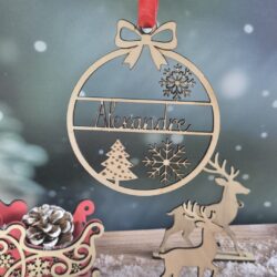 Boule de Noël en bois avec le prénom Alexandre découpé, suspendue devant un fond enneigé