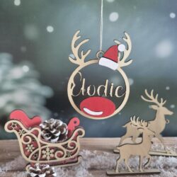 Boule de Noël en bois avec le prénom Elodie découpé, décor père noël, suspendue devant un fond enneigé