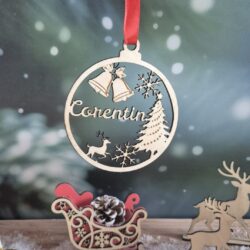 Boule de Noël en bois avec le prénom Corentin découpé, suspendue devant un fond enneigé