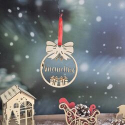 Boule de Noël en bois avec le prénom Amandine découpé, suspendue devant un fond enneigé