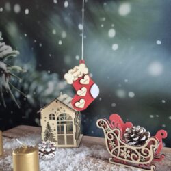 Décoration de Noël en bois en forme de chaussette rouge, personnalisée avec un nom de famille et des prénoms sur des cœurs.