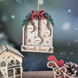Décoration de Noël en bois en forme de fenêtre, avec trois prénoms sur des boules et un nom de famille gravé.