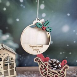 Boule de Noël porte-photo en bois, décorée de houx et gravée « Joyeux Noël 2026 », avec un emplacement vide pour une photo.