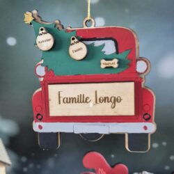 Détail de la décoration de Noël en bois en forme de voiture rouge transportant un sapin, personnalisée avec des prénoms et un nom de famille.