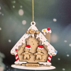 Maison de Noël en bois façon pain d’épices, avec deux personnages gravés de prénoms et un nom de famille.