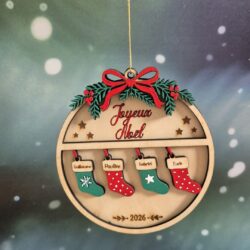 Boule de Noël en bois avec quatre petites chaussettes colorées gravées de prénoms et l’année 2026.