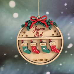 Boule de Noël en bois avec quatre petites chaussettes colorées gravées de prénoms et l’année 2026.